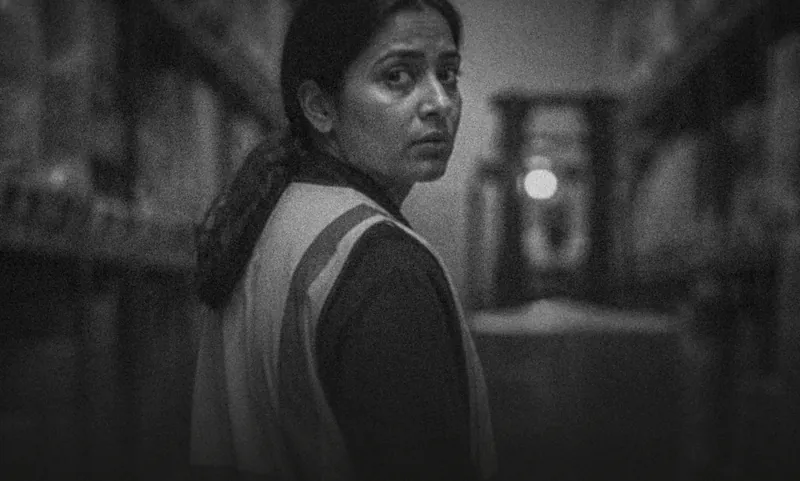 A woman in a hi-vis vest in a warehouse, looking back over her shoulder