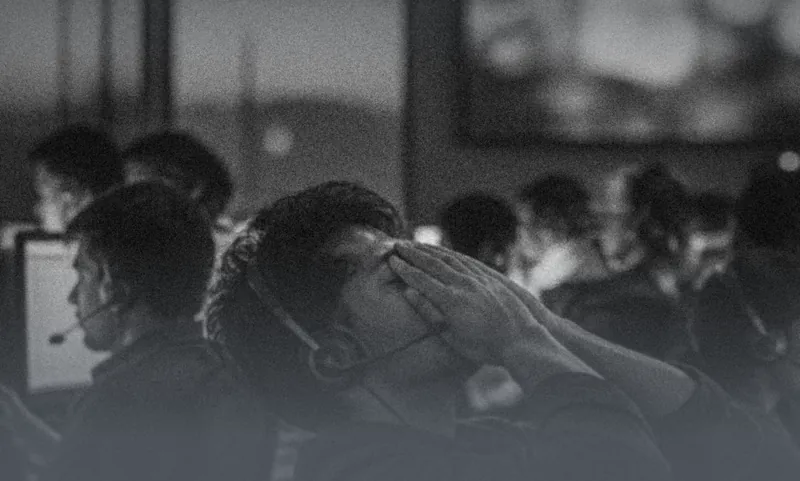 Office workers at their desks, one with his head in his hands