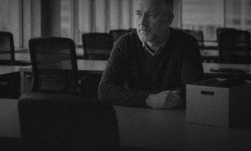 A man sitting alone at a desk beside packing boxes