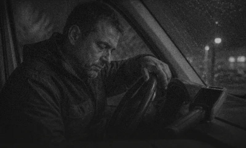 A man sitting in his car at night